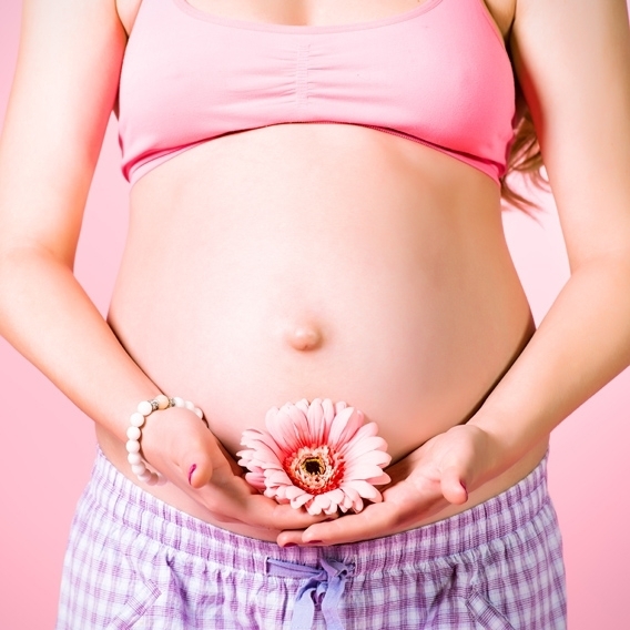 Mujer embarazada sujetando flor